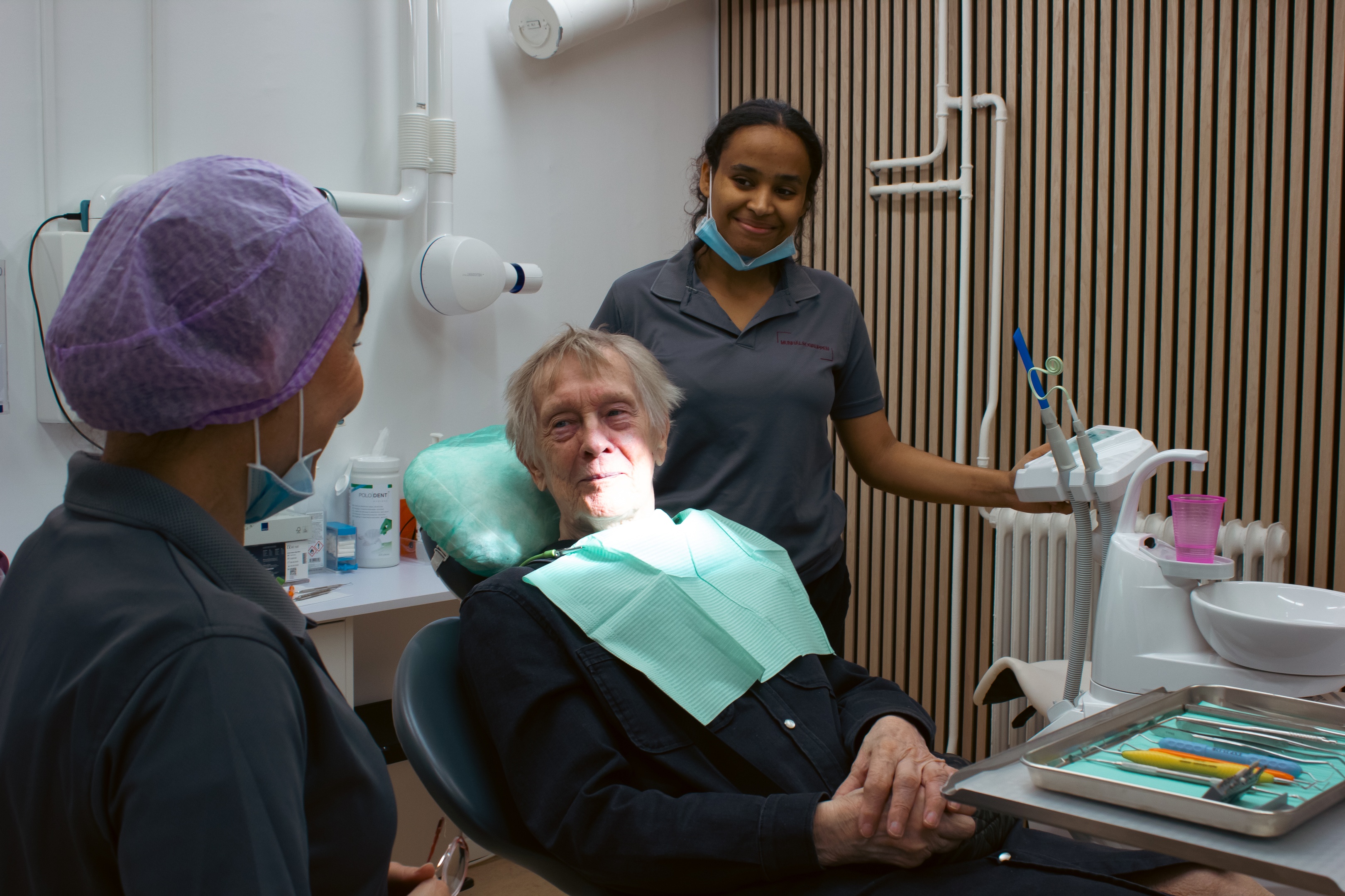 Closeup portrait of smiling senior black male patient holding dental mirror tool, posing with female dentist during checkup appointment